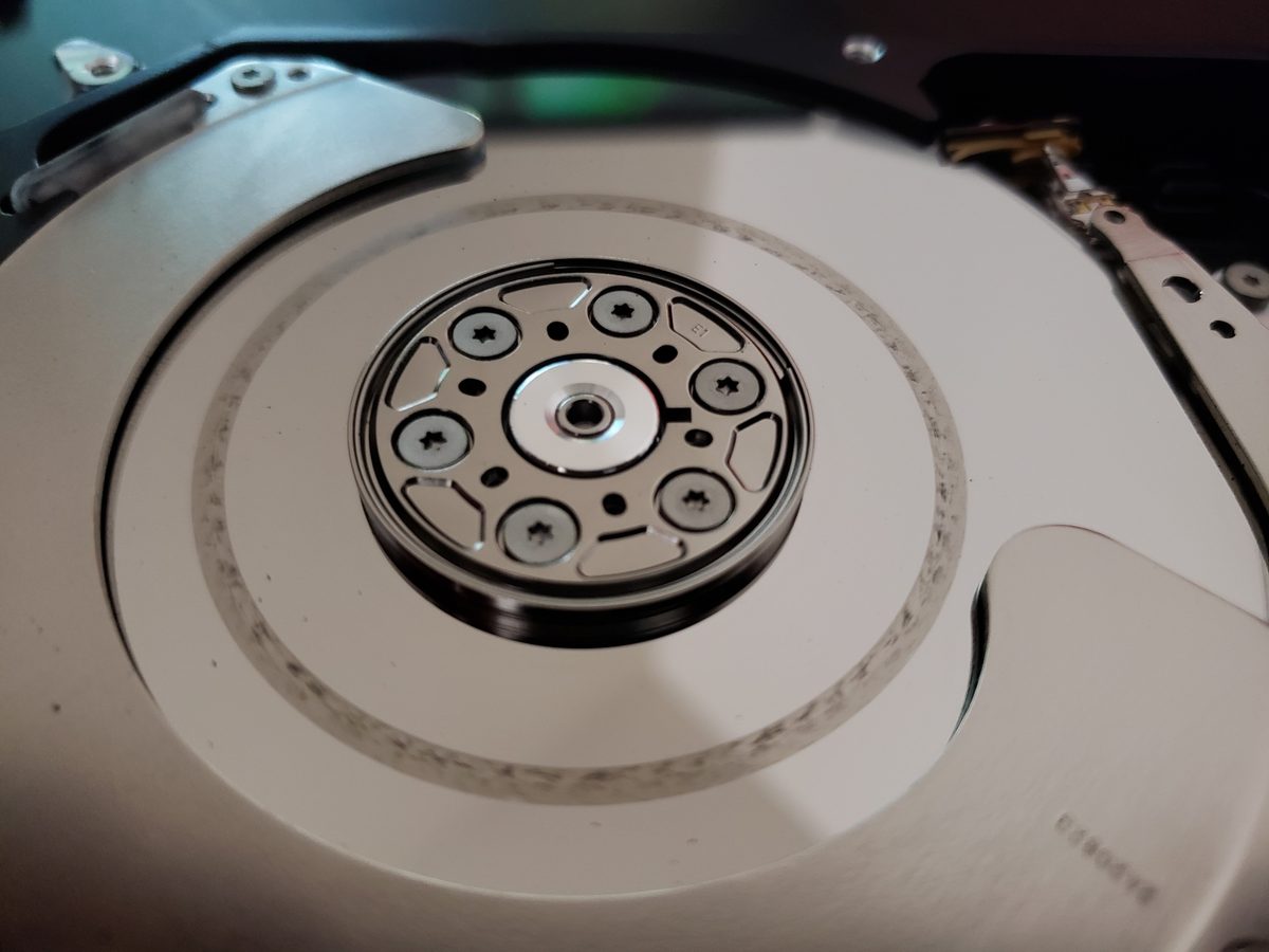 Intérieur d'un disque dur HDD avec plateau, bras de lecture et axe moteur visibles