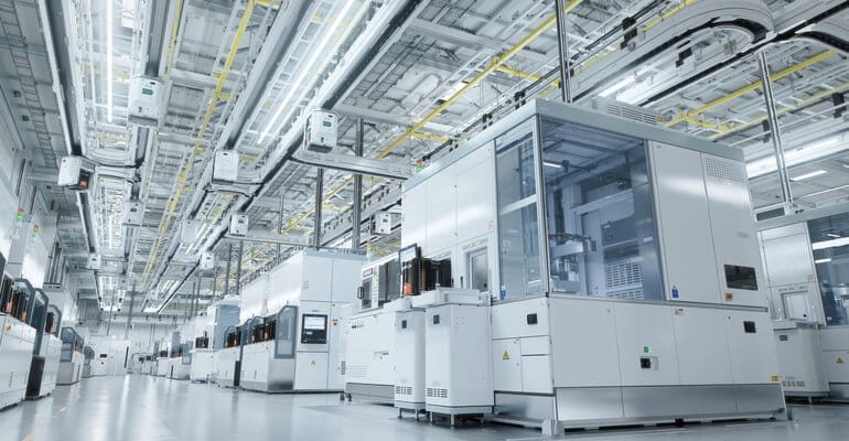 Salle blanche industrielle pour assemblage électronique : opérateurs en combinaison sur ligne de production
