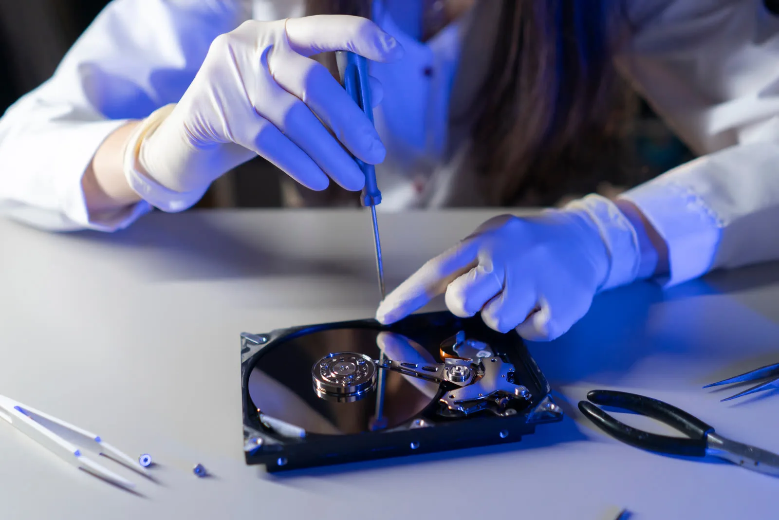 Personne manipulant un disque dur ouvert avec un outil de précision